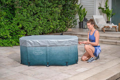 A woman is setting up an inflatable Ice tub outdoors on a patio.