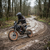 A person riding a motorcycle on a muddy forest road