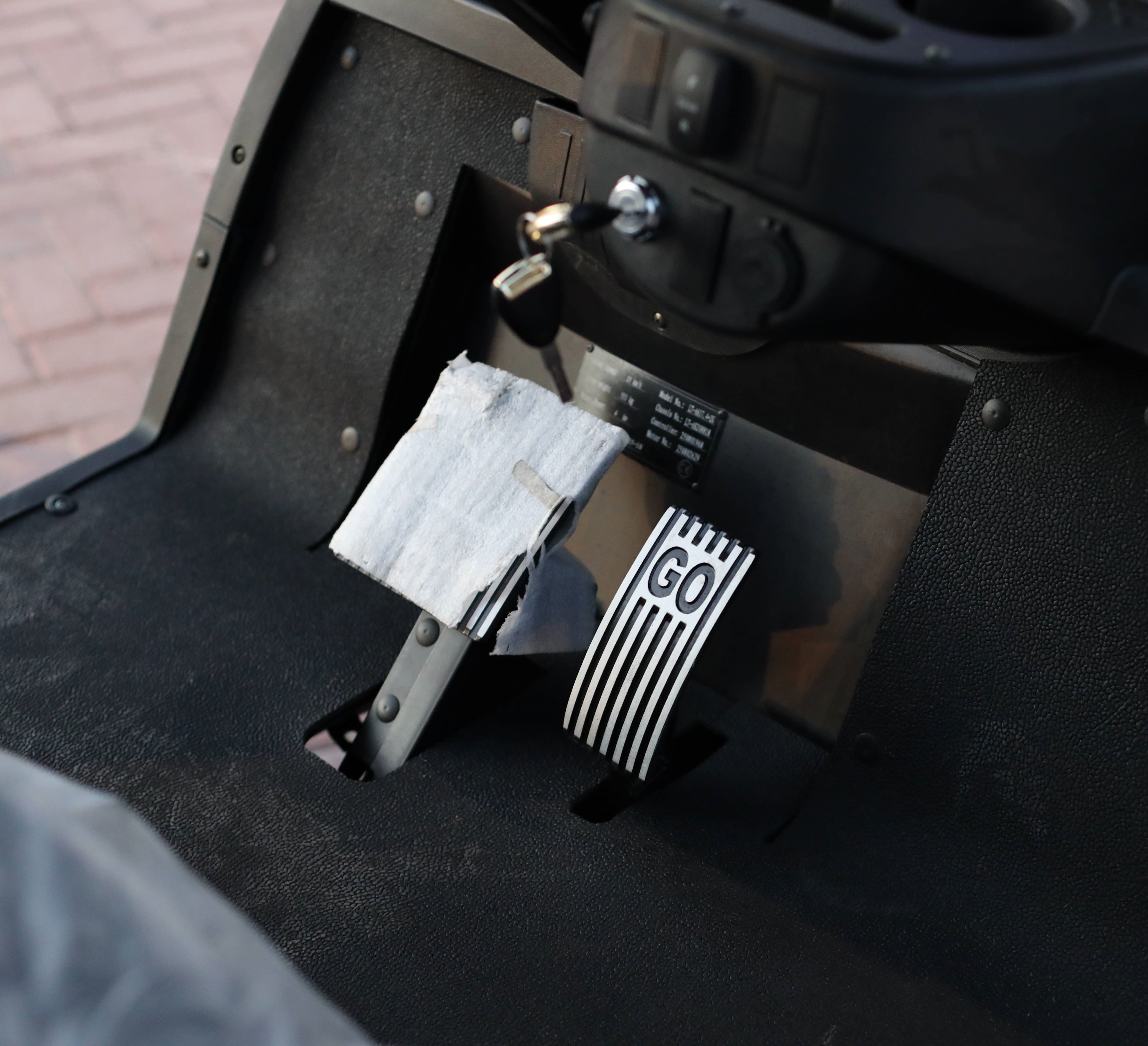 Close-up of golf car pedal with 'GO' branding on a black interior background
