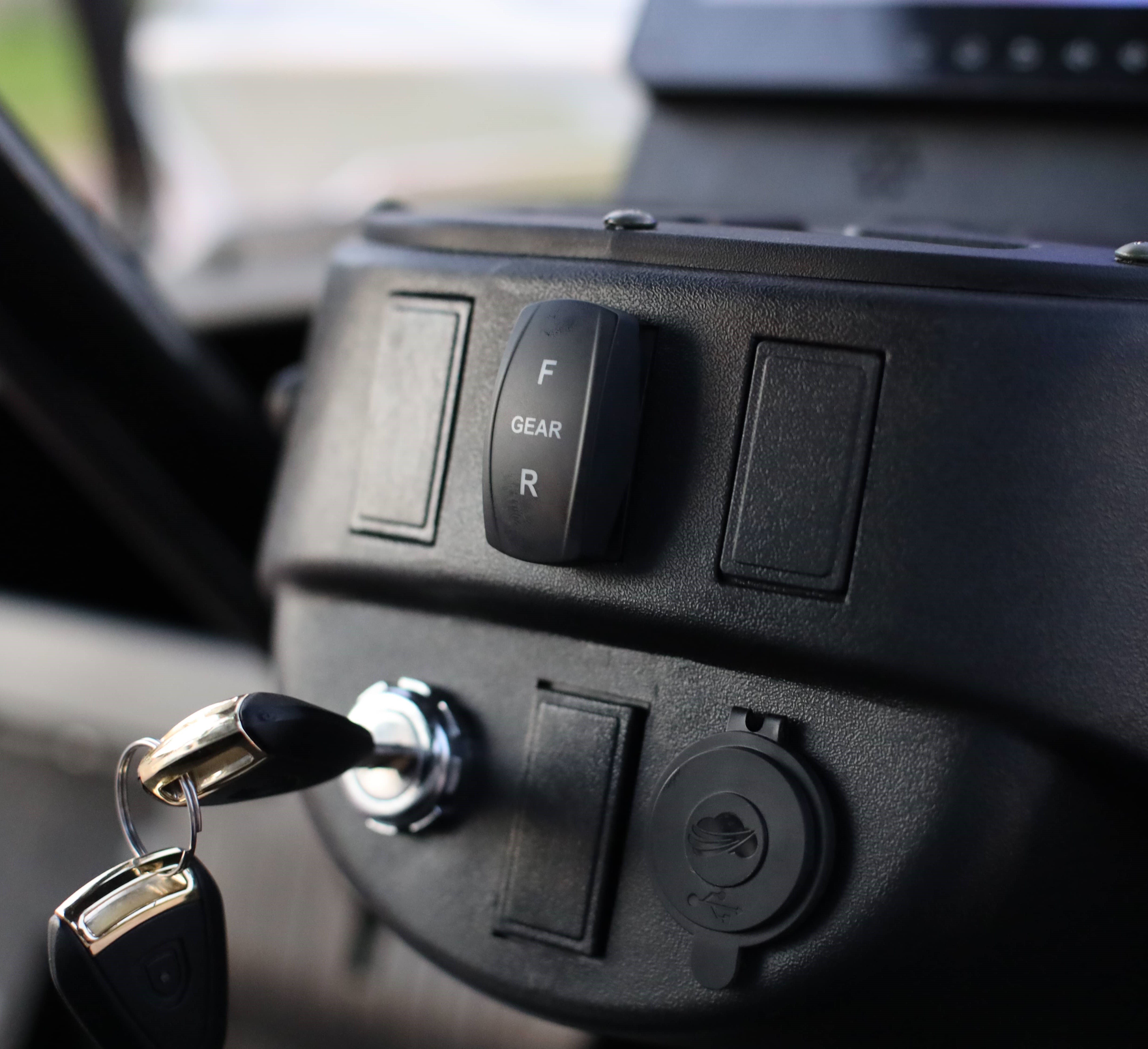 Car key inserted into ignition with gear and brake lights visible on the Keon golf cart