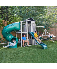 Kidkraft Wrangler  Children playing on a playground set with a green slide and swing set in a backyard.