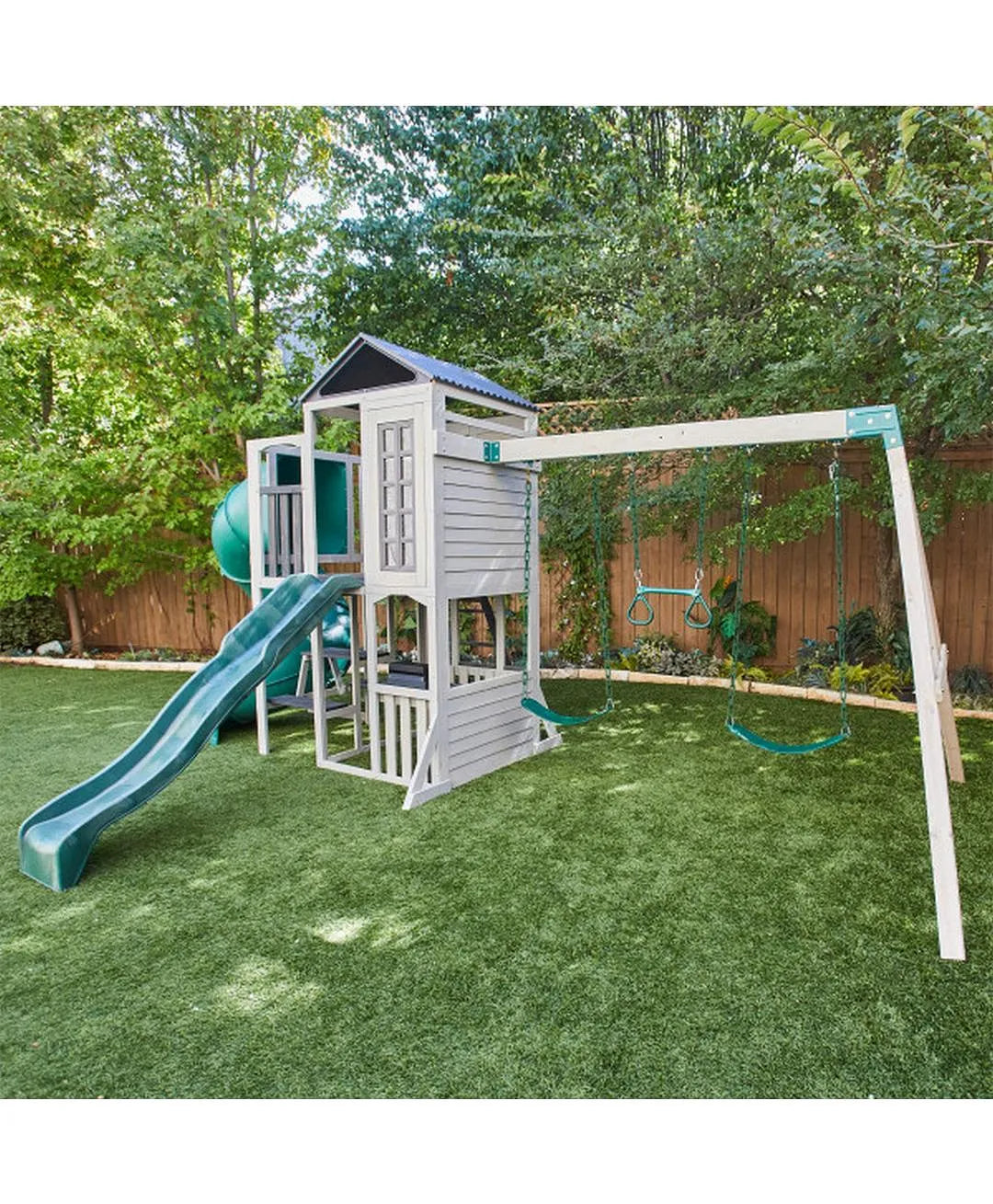 Kidkraft Wrangler Way Swing Set, Wooden Playhouse on grassy area with trees in the background