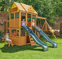 Kidkraft Overland Heights Children playing on a wooden playset with  2 slides and play benches  in a backyard.
