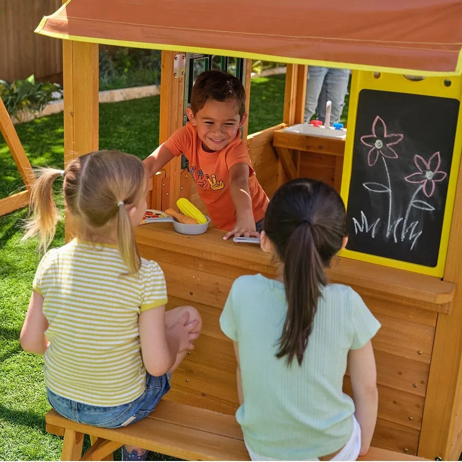 Kidkraft Overland Heights Children playing in a wooden playhouse with a chalkboard wall.