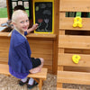 KidKraft Charleston Child drawing on a chalkboard in a wooden playhouse