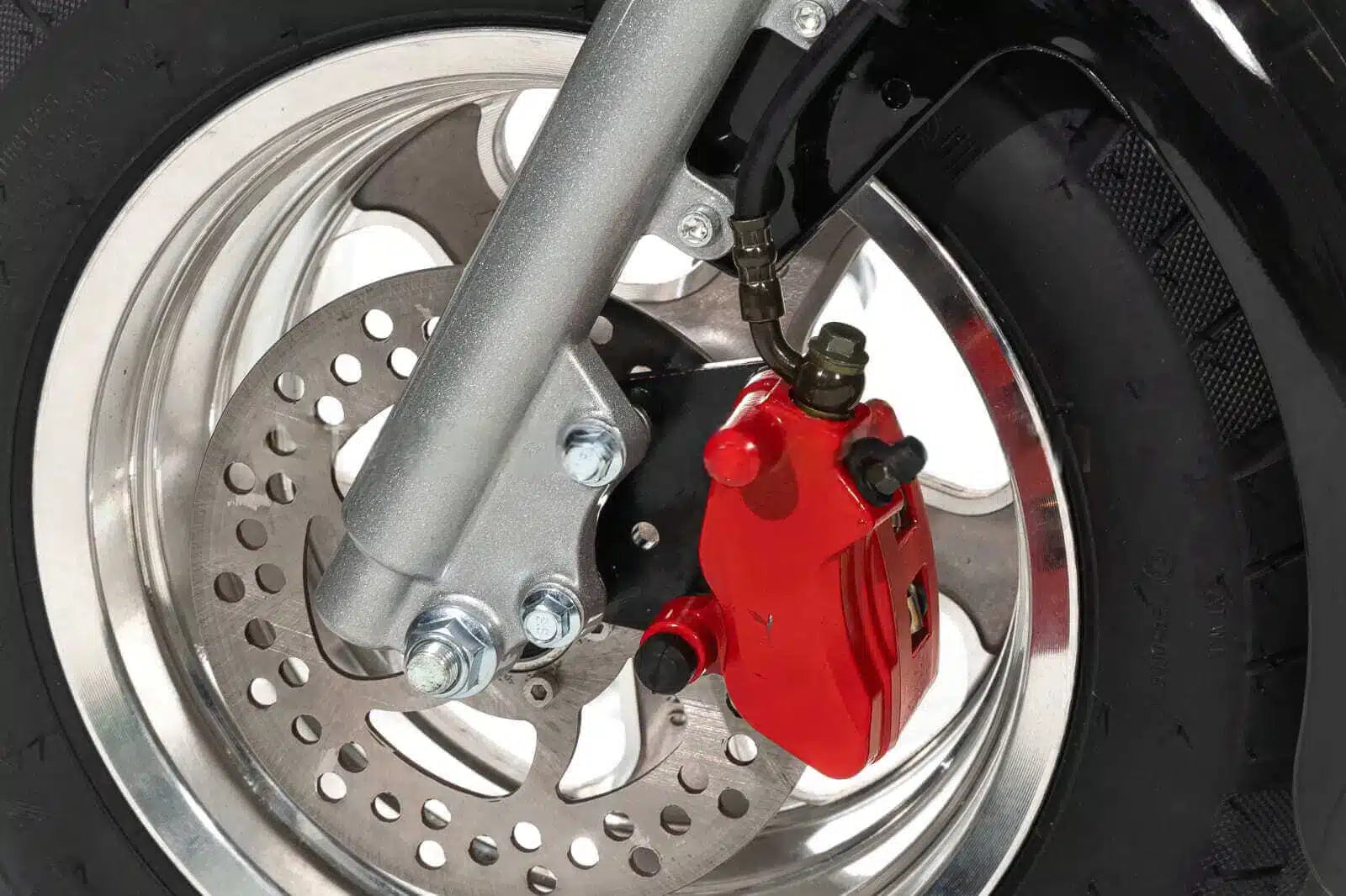 Close-up of a motorcycle wheel with red brake caliper and silver disc brake.