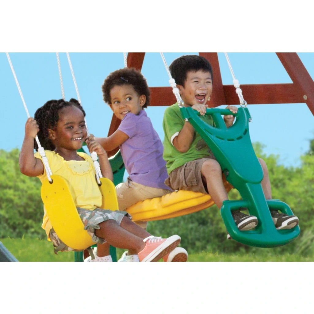 KidKraft Ridgeview Deluxe Clubhouse Three children on a colorful swing set with a clear blue sky and greenery in the background.