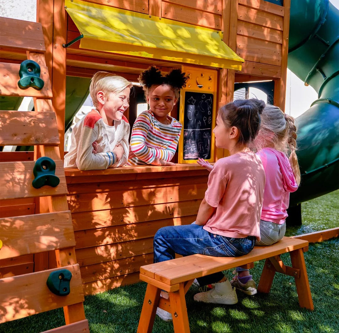 Children playing at a KidKraft Falcon Ridge Wooden with a yellow slide and window.