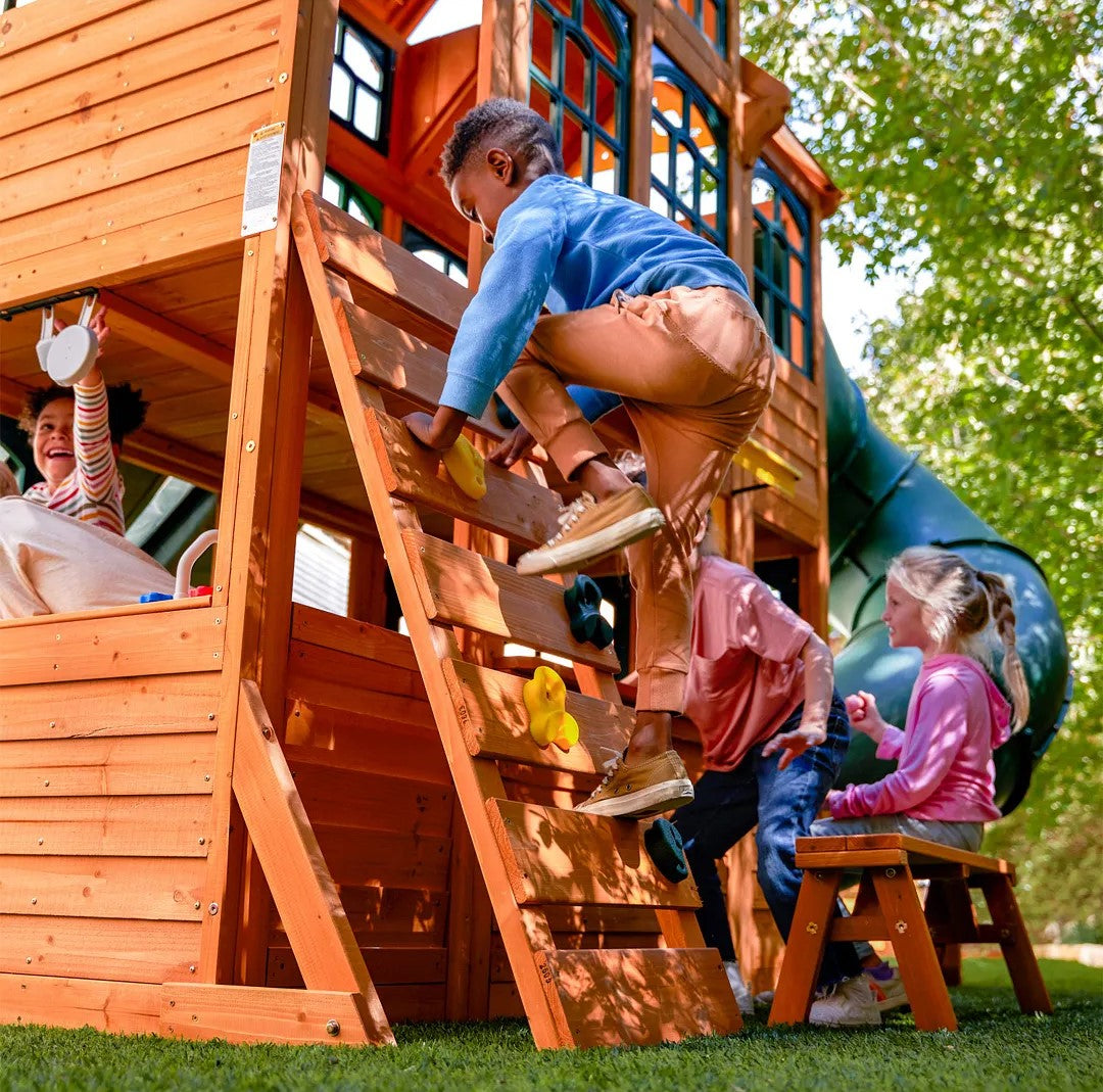 Children playing on a wooden playground set with slides and climbing structures. KidKraft Falcon Ridge Wooden
