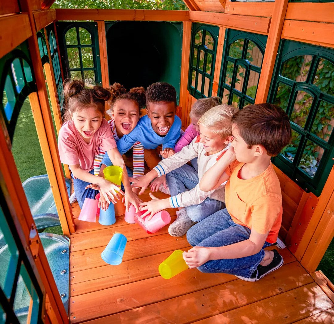 Children playing with colorful cups inside a KidKraft Falcon Ridge Wooden.