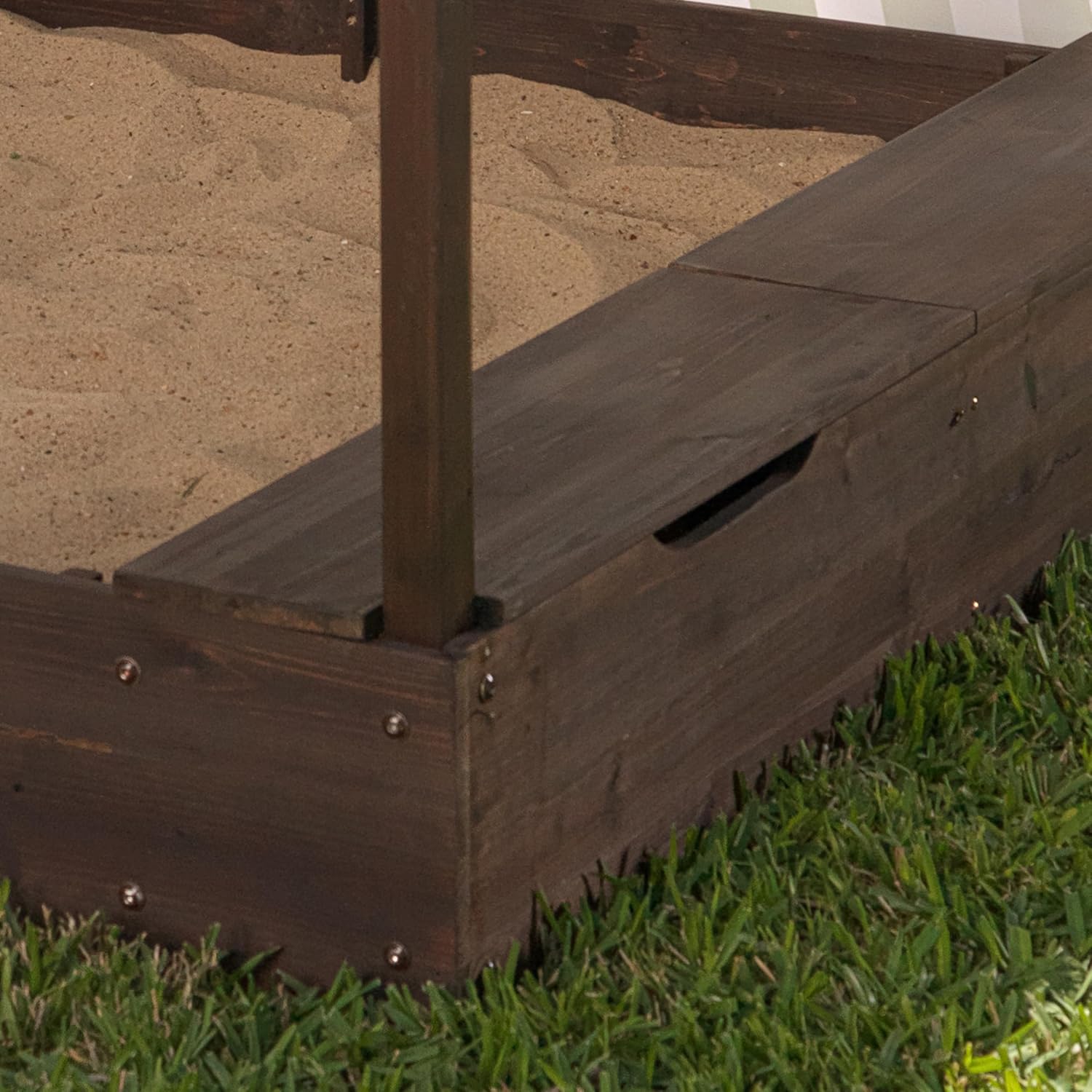 Wooden garden bed with metal stakes on grass and sand 