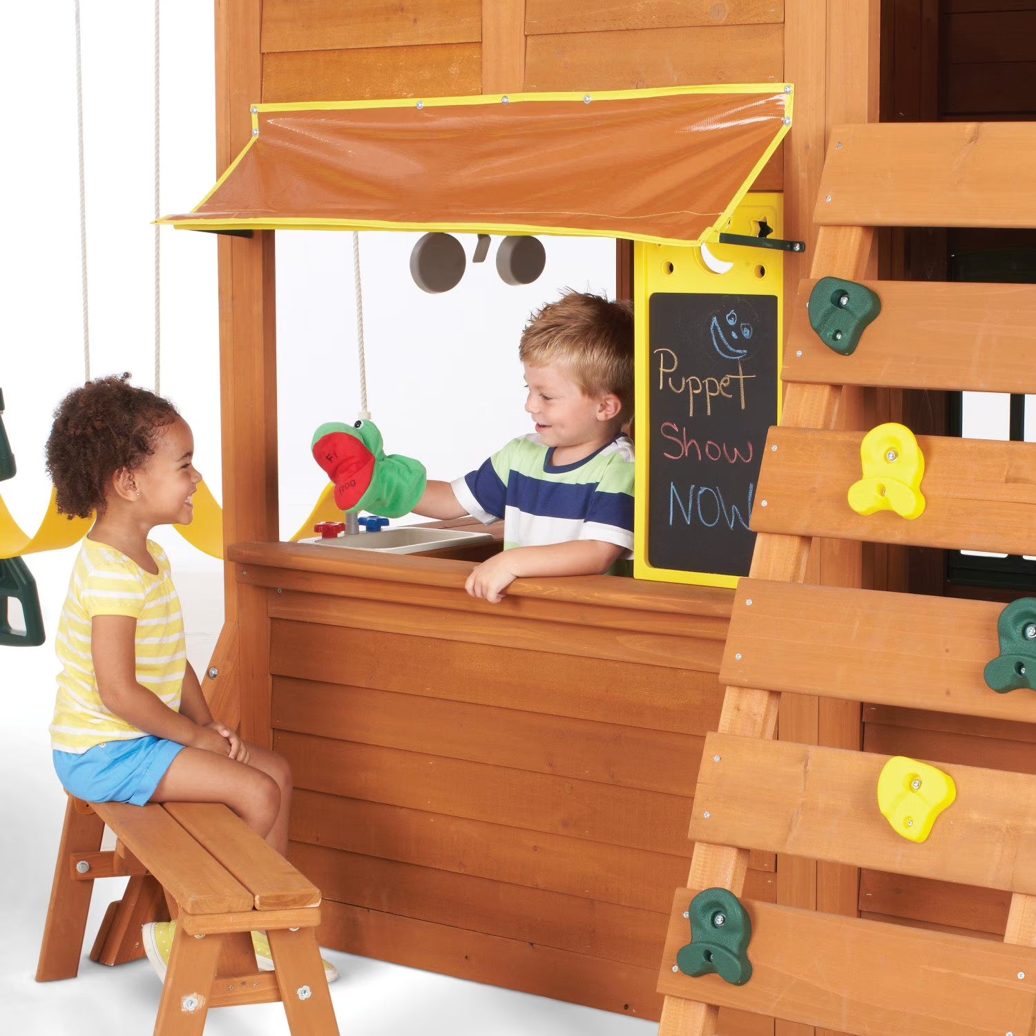 Children ROLE  playing with a wooden playhouse that has a puppet show setup.