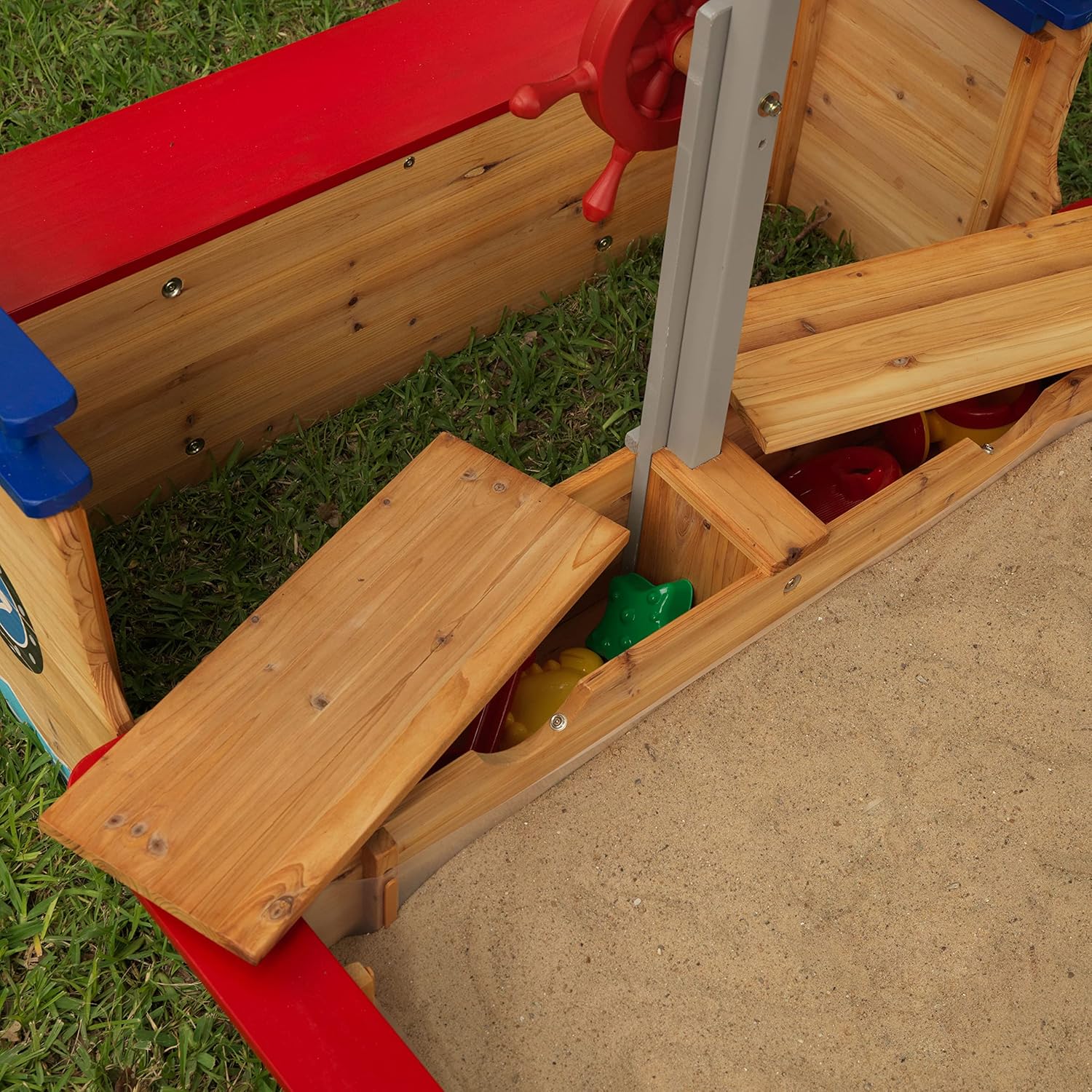 Children's play structure with sand area and toys on grass