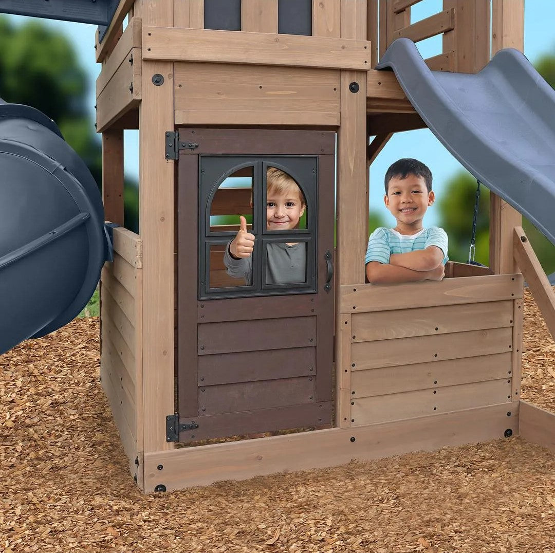 Gorilla Playsets Skyline Lookout Children playing on a wooden playset with a slide and window.