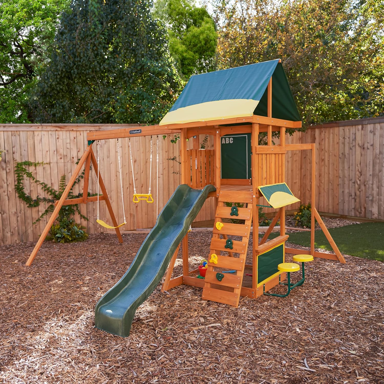 Kidkraft Brightside  Wooden playset with green slide and canopy in a backyard 
