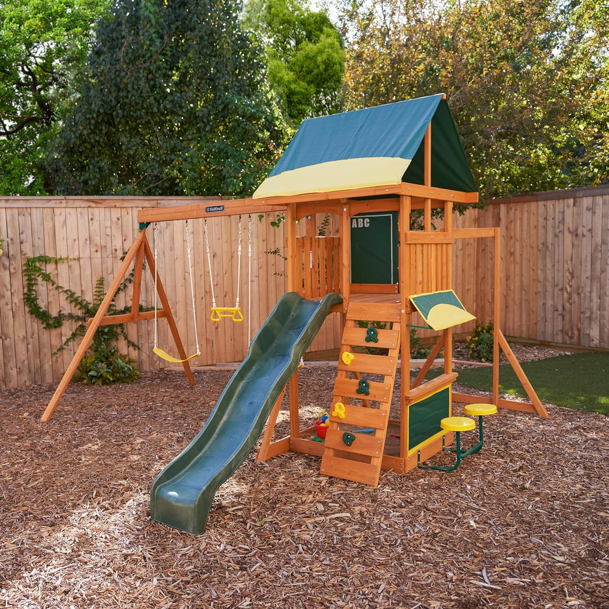 Kidkraft Brightside  Wooden playset with green slide and canopy in a backyard 