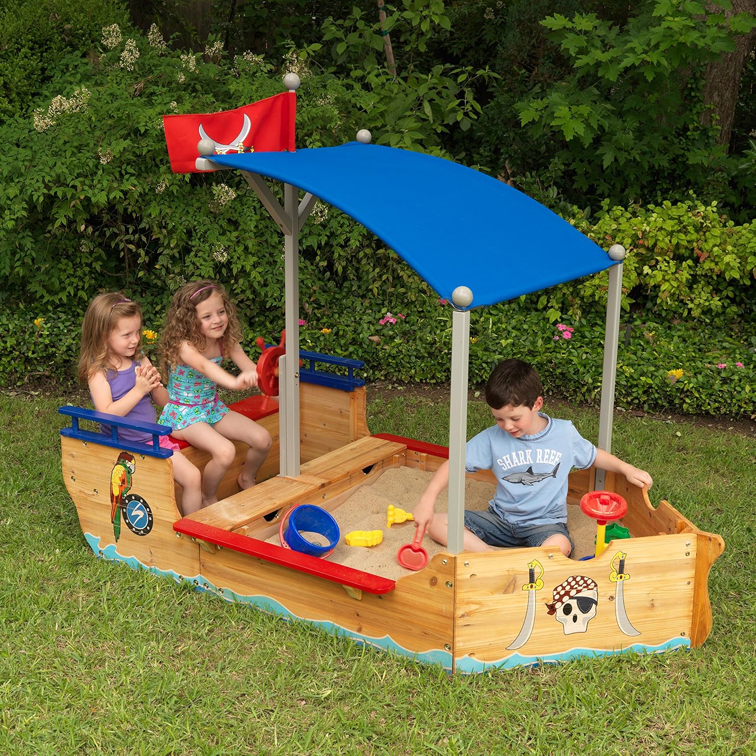 Children playing in a wooden pirate ship sandbox with a canopy