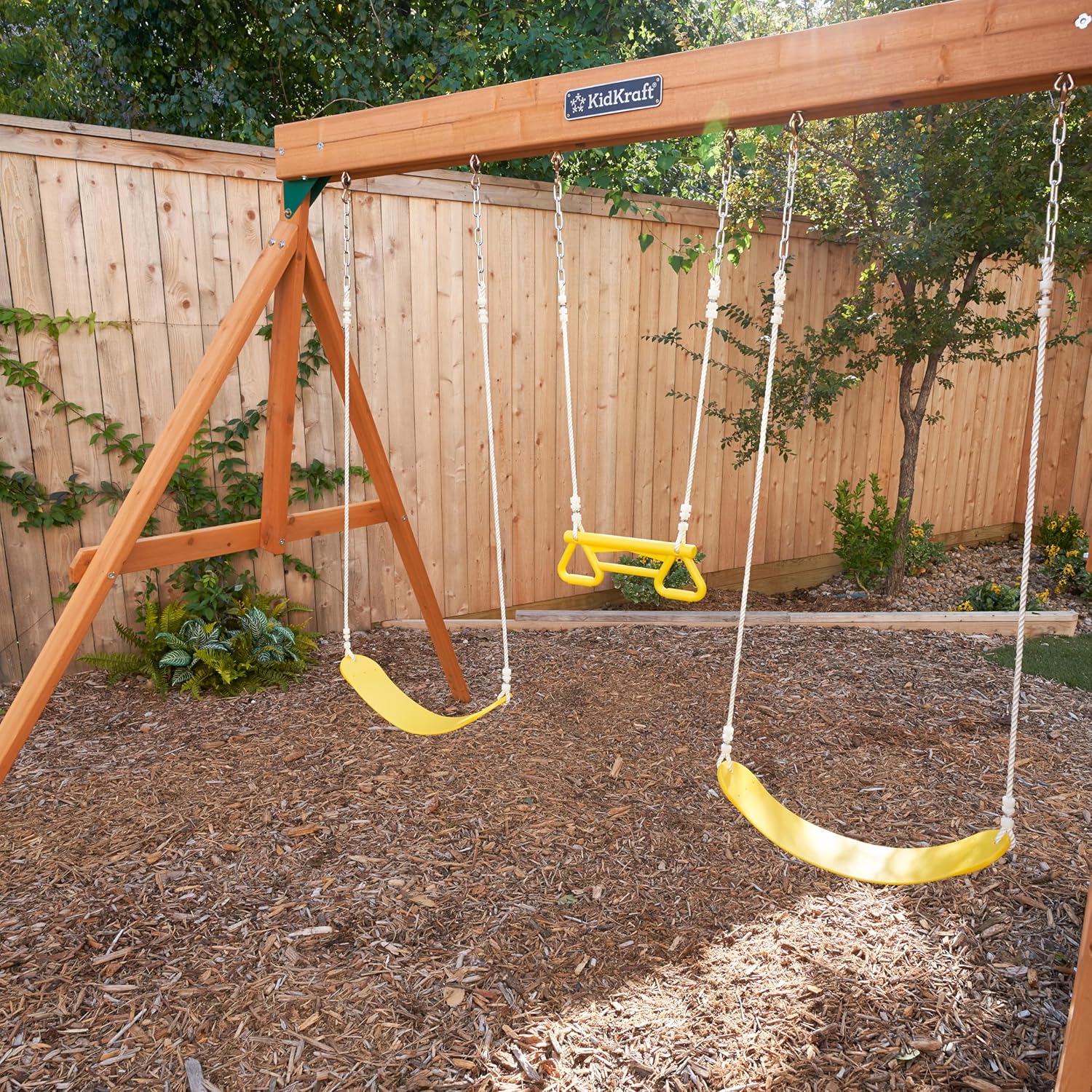 Kidkraft brightside wooden swing set with yellow seats in a backyard setting