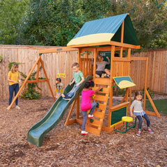 Kidkraft Brightside Children playing on a wooden playset with a slide in a backyard setting.