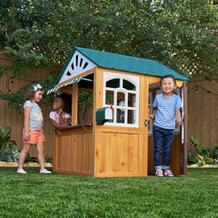 Children playing in a wooden playhouse with a green roof 