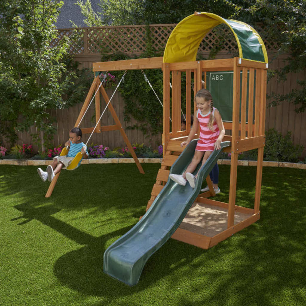 Kidkraft Ainsley Outdoor Playset Children playing on a wooden swing set with a slide in a backyard.