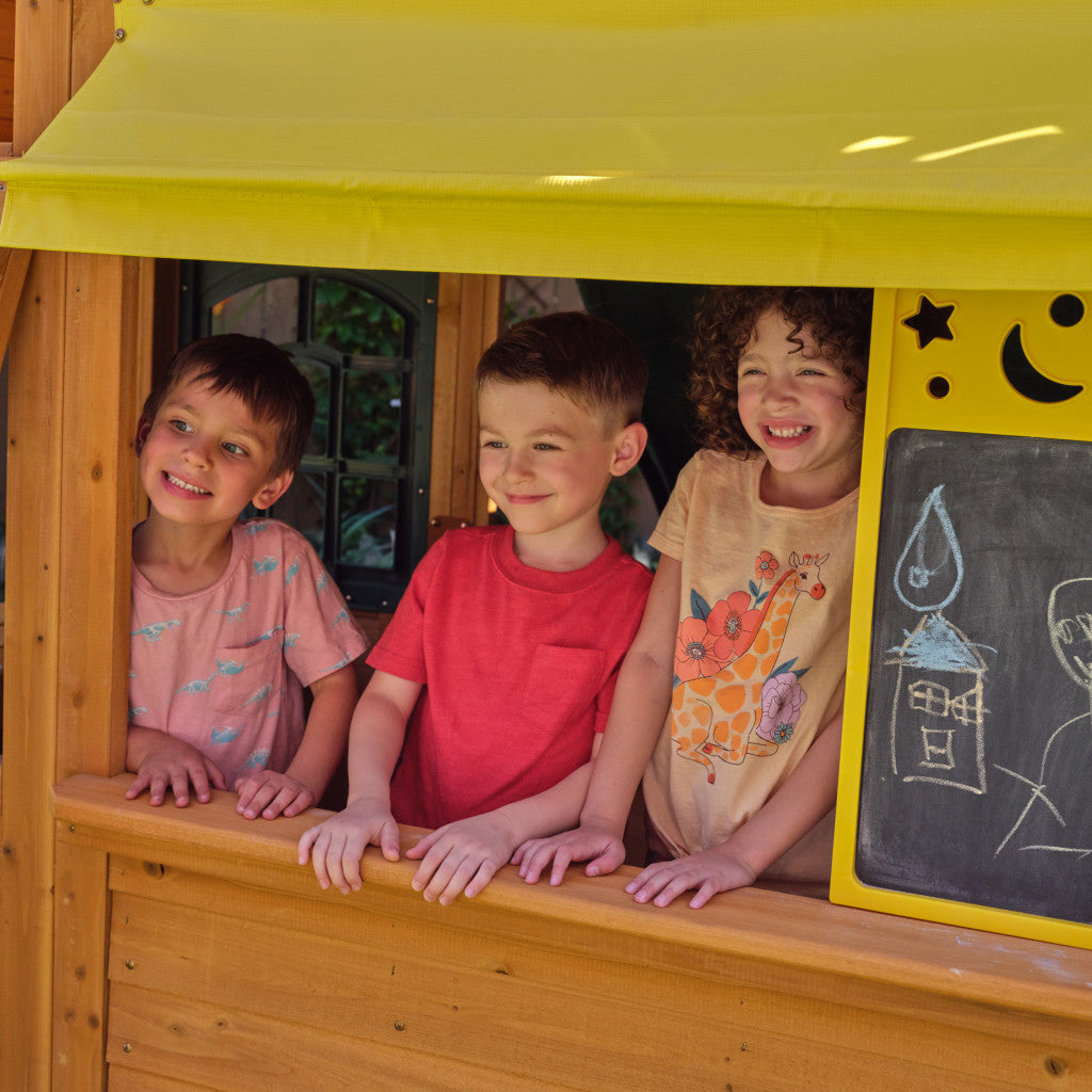 Three children peeking out from KidKraft Bear Cave 