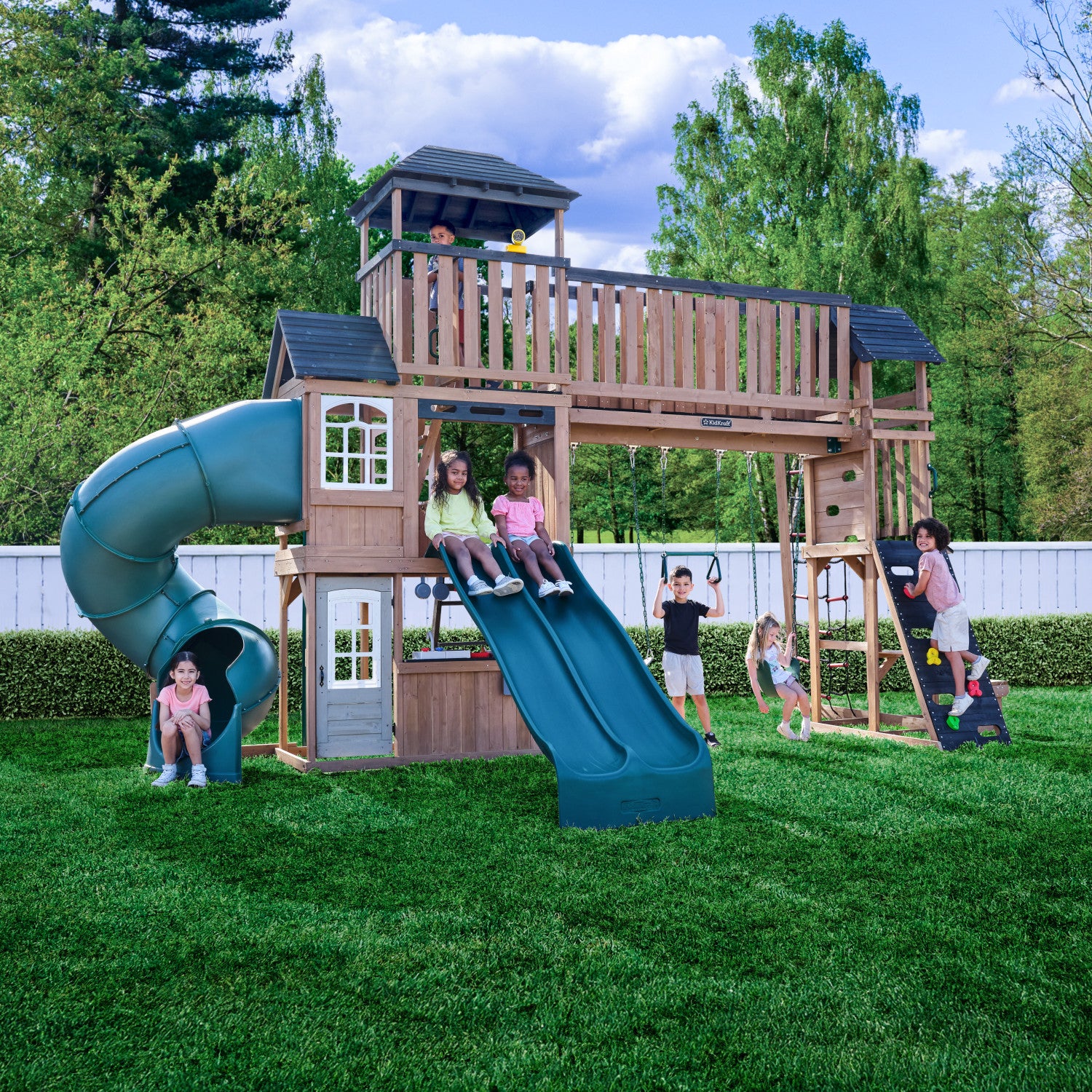 Children playing Treetop Observatory Wooden Swing and Slide Playset in backyard setting.