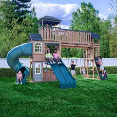 Children playing Treetop Observatory Wooden Swing and Slide Playset in backyard setting.