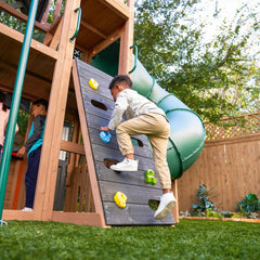 KidKraft Summit, Children playing on a wooden playground set with a slide and climbing wall.