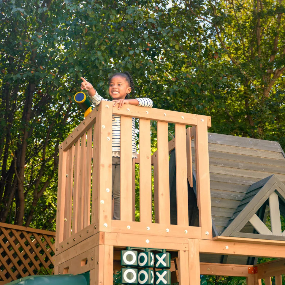 KidKraft Summit View Swing Playset Child on a wooden playset with trees in the background