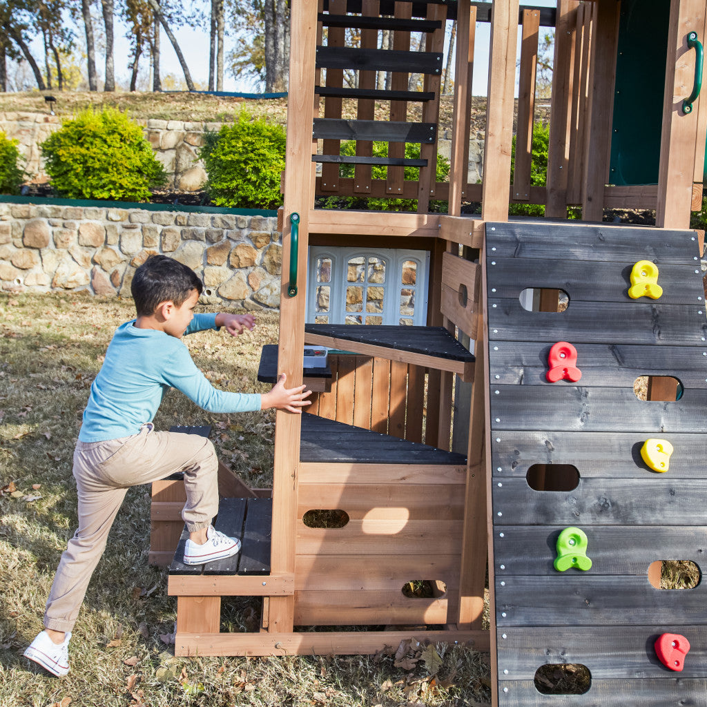Kidkraft Child climbing a wooden play structure with colorful climbing elements in an outdoor setting.
