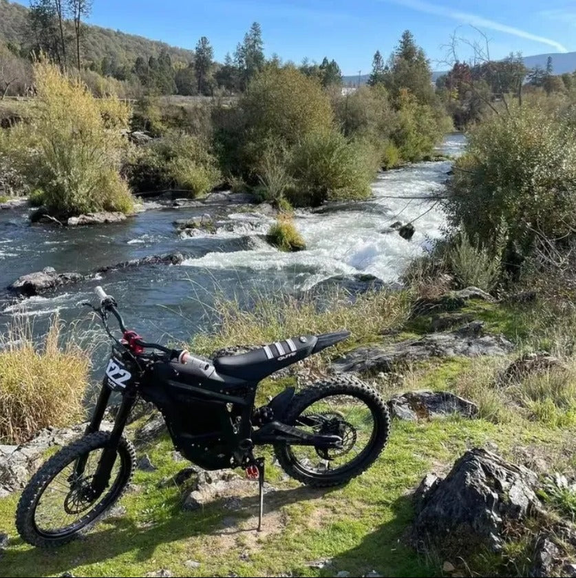 A black off-road Talaria Sting MX5 Desert Beast Electric Dirt Bike is on a rocky Area
