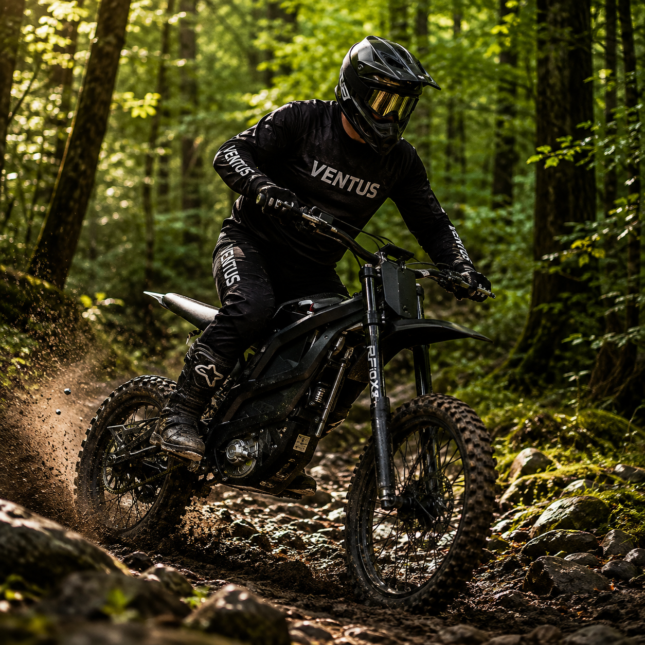 A rider riding in black Ventus motocross gear rides a black dirt bike on a rocky forest trail