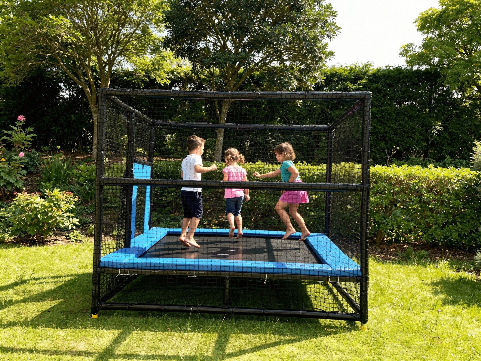 Children playing on a trampoline in a garden with greenery around