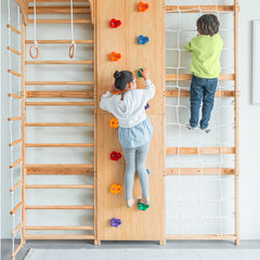Two children are climbing on a wooden Swedish Ladder Wall Gym Set