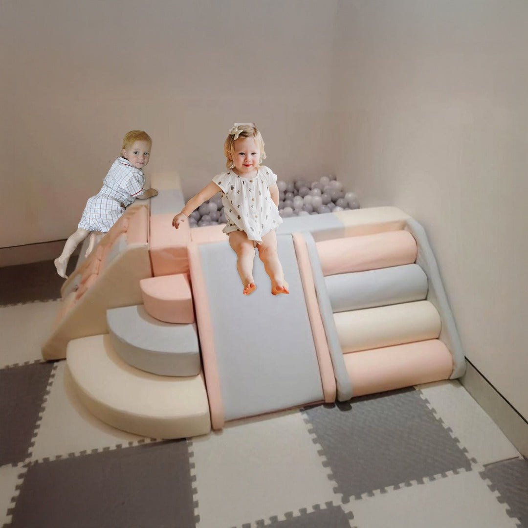 Toddler sliding on a pastel foam play set with another child