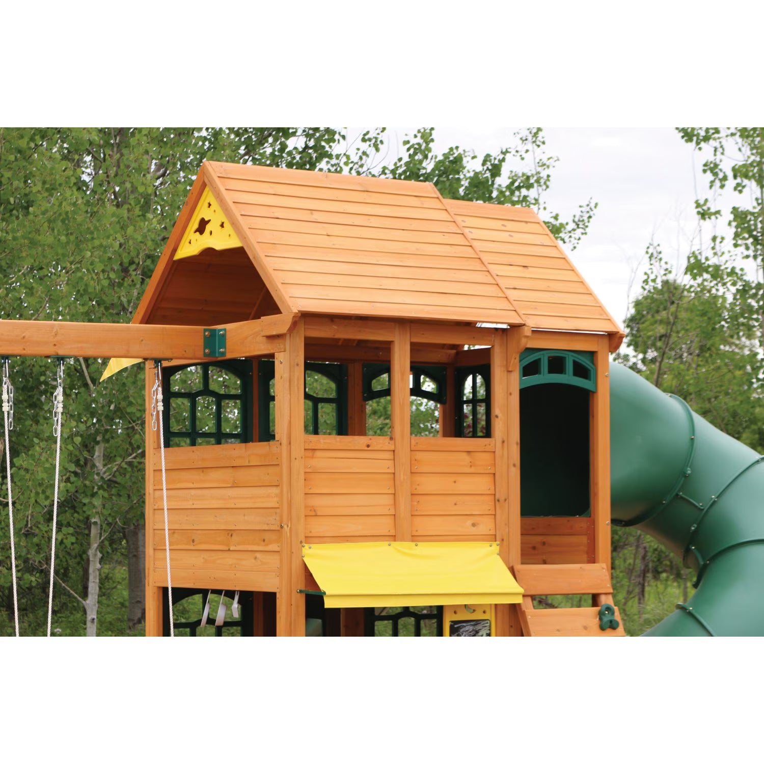 KidKraft Charleston Lodge Fort Wooden Outdoor Swing Set with a green slideand rooftop playarea  in a park setting