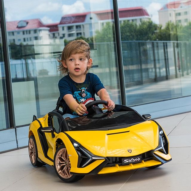 A child sitting in a yellow toy car