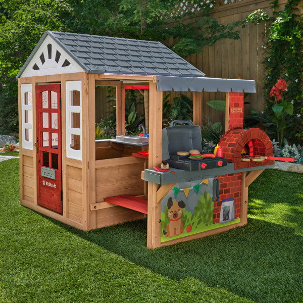 Wooden playhouse with kitchen and pizza oven grill in garden