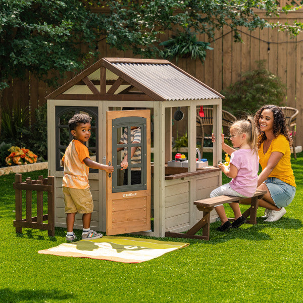 Children playing outside a KidKraft Pioneer Cottage Wooden Playhouse