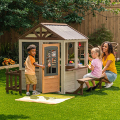 Children playing outside a KidKraft Pioneer Cottage Wooden Playhouse