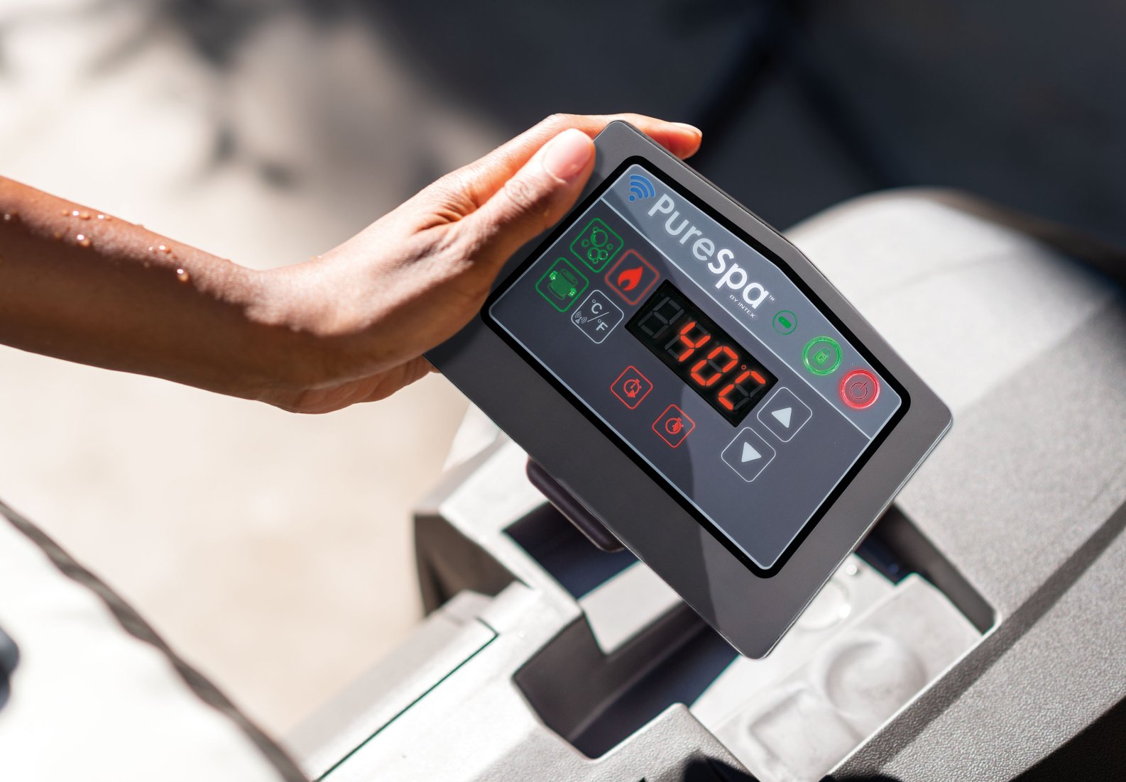 Hand holding a PureSpa control panel with digital display