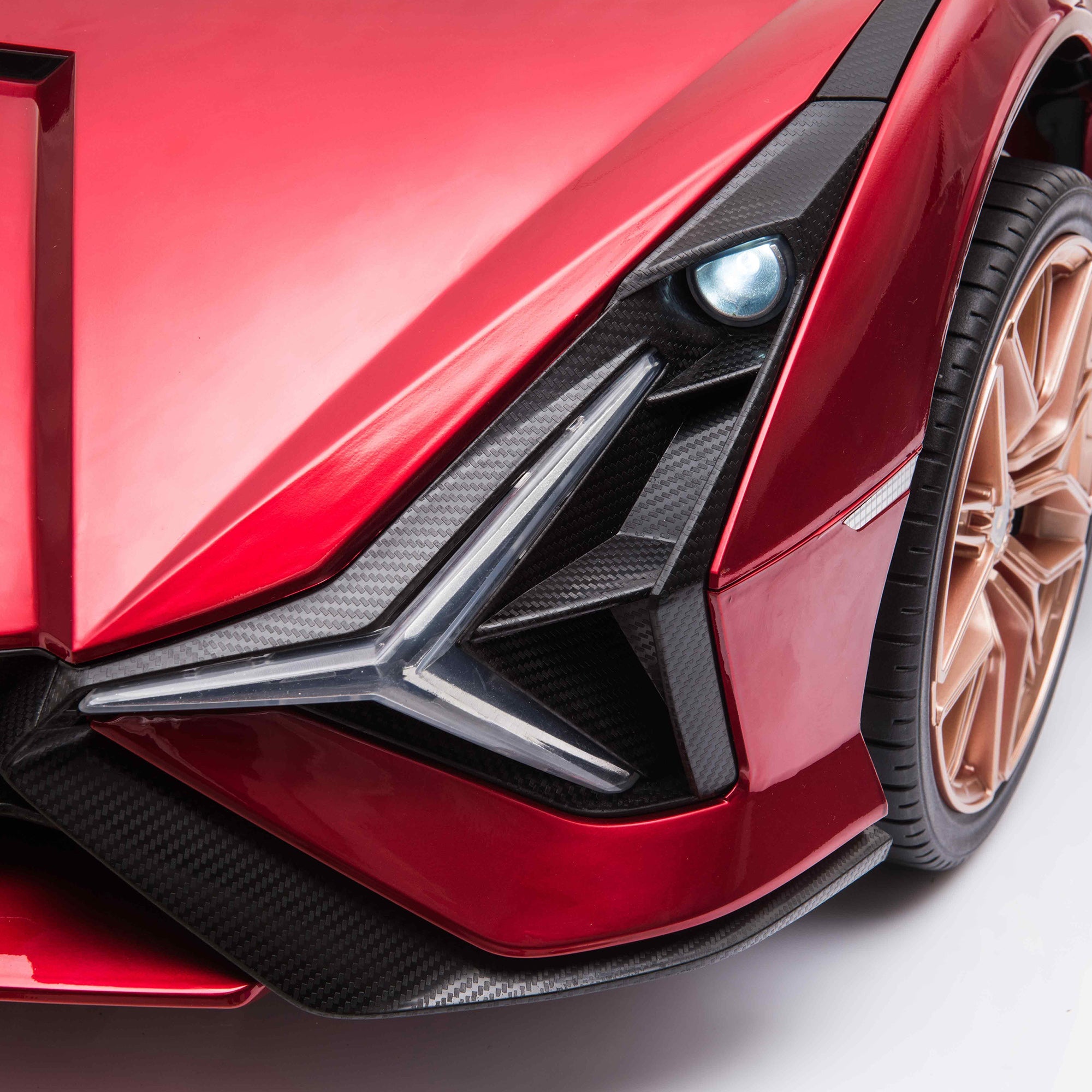 Close-up of a red sports car's front end with a focus on the grille and wheel.