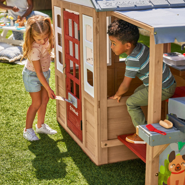 Children playing with a wooden playhouse in a grassy Play area