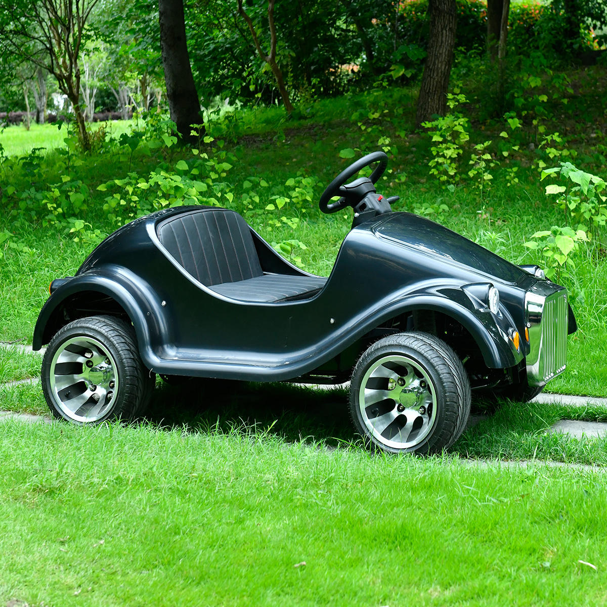 Side view of Black vintage 150 cc buggy car with a chrome grille from the front on a grassy path.
