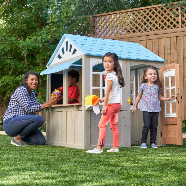 Children playing outside in a wooden playhouse