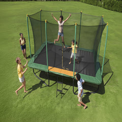 Children playing on a trampoline with safety net in a grassy area
