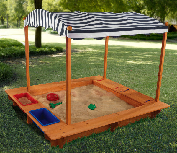 Wooden sandbox with a striped canopy on a grassy Play Area