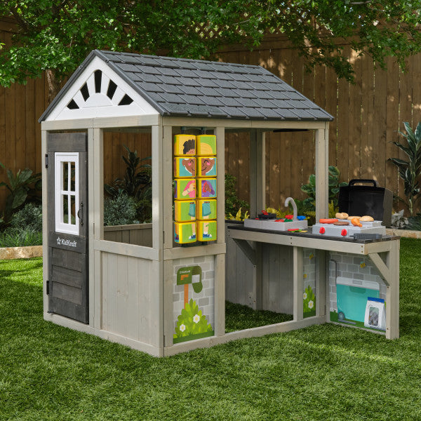 Children's playhouse with toy kitchen set on a grassy kids' playground